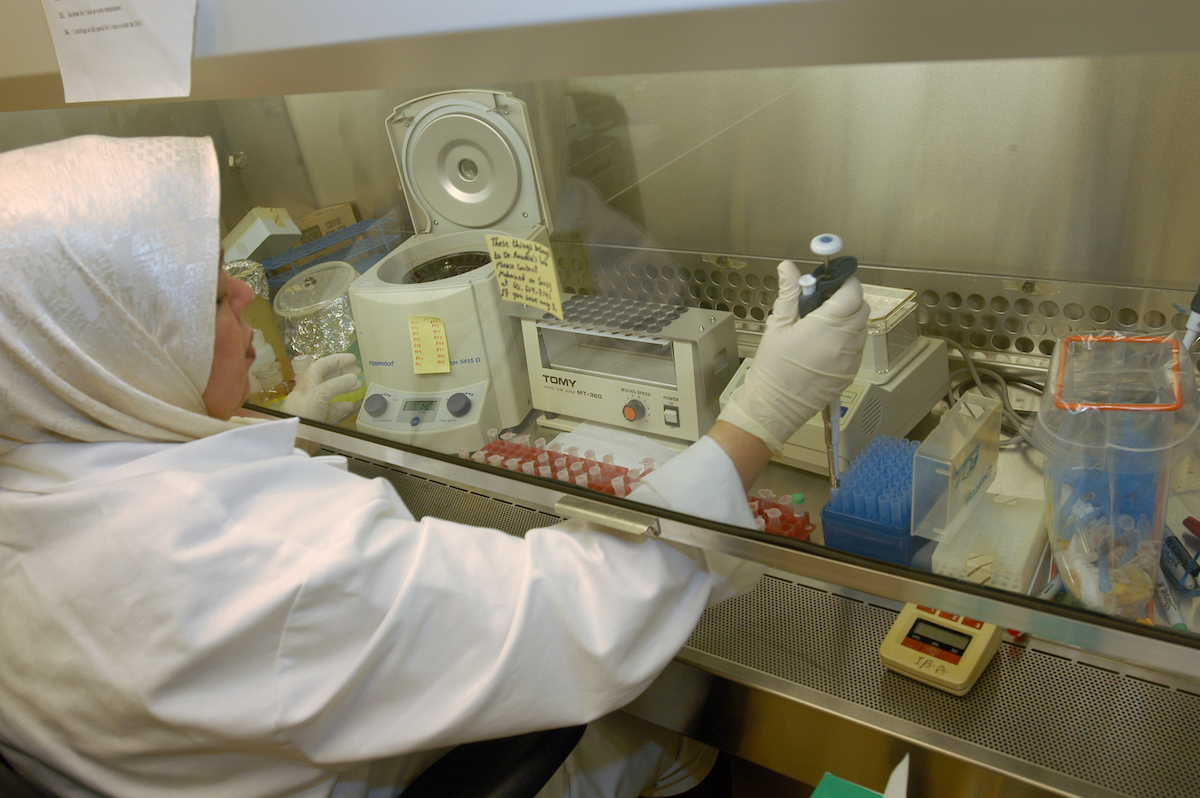 Researcher using a pipette in a vent hood.